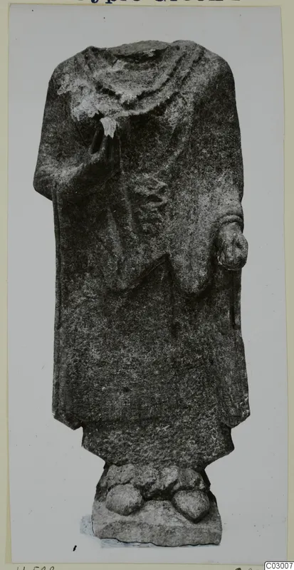 Headless limestone statue of a standing figure in a long draped garment, on a rough base, from Vouni