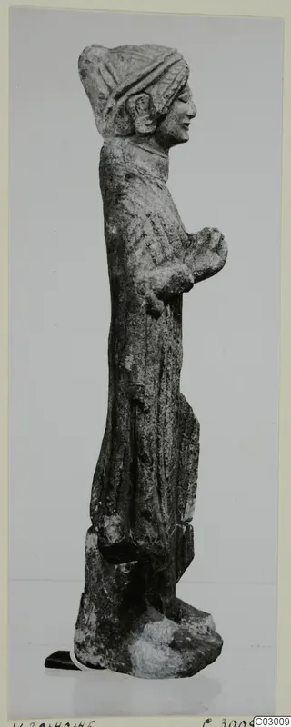Limestone standing figure from Vouni, seen in profile, with a headdress and long garment