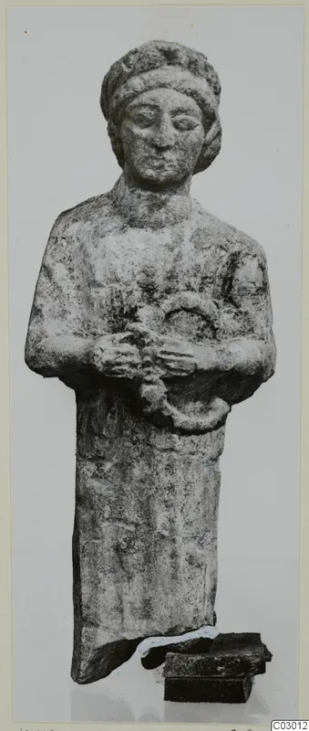Small limestone standing figure from Vouni, arms folded across the chest and hands holding a ring-shaped object.
