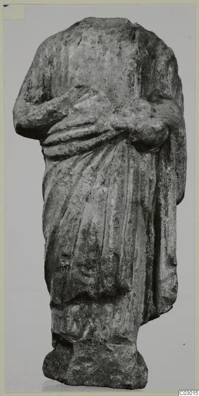 Headless limestone draped statue of a standing figure, arms folded across the body, from Vouni.