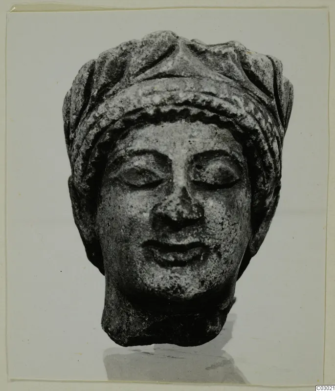 Limestone head from Vouni with downcast eyes and a banded headdress, shown from the front.