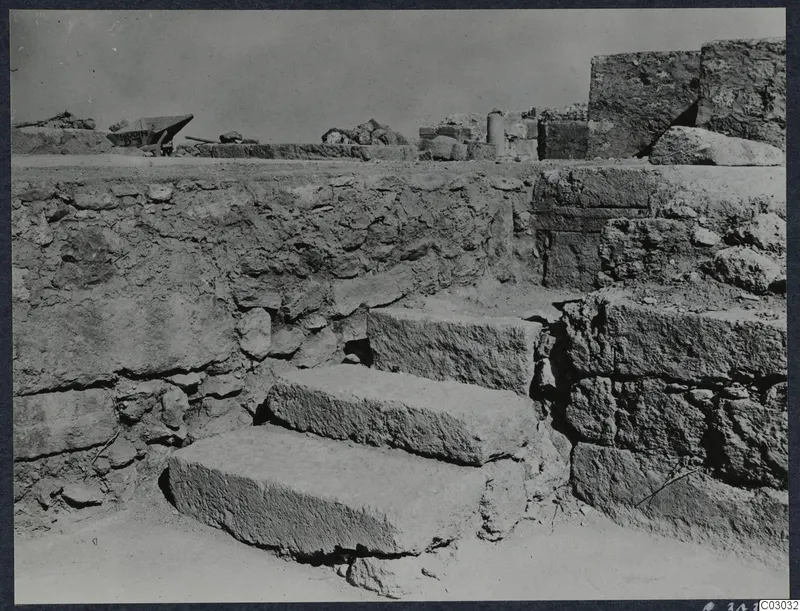 Stone steps leading up between ancient masonry walls at the palace at Vouni, with ruined walls behind.