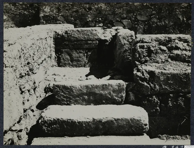 Stone steps leading up to a dark opening, with rough stone walls on either side, at the palace at Vouni