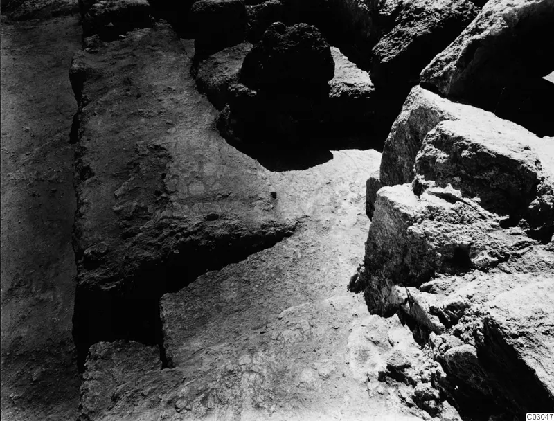 Large stone blocks and rubble during excavation at the palace at Vouni, with a pale flat surface between them