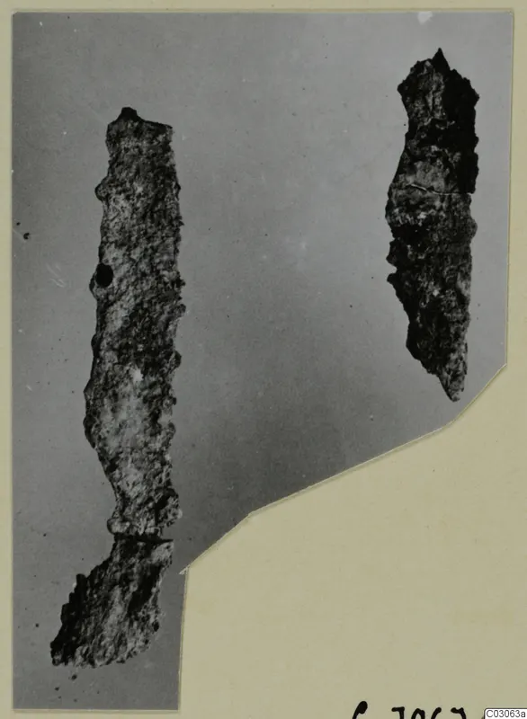 Two corroded iron tools lying upright on a grey backdrop