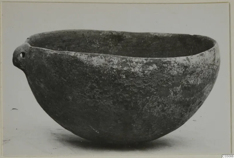 Pottery Black Slip Ware bowl with a small pierced lug handle, shown against a plain light background.