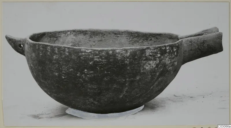 Black Slip Ware bowl with two horizontal handles, photographed from the side on a pale background.