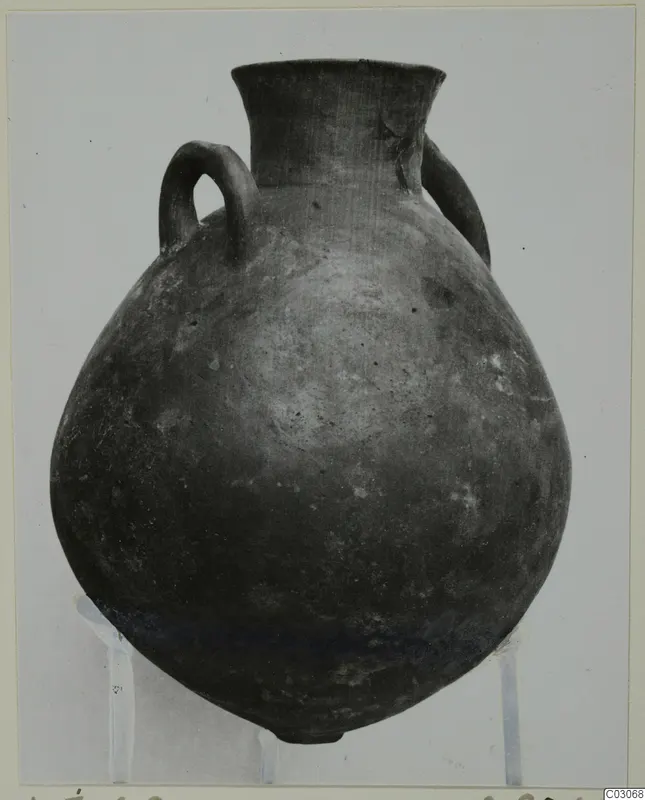 Black Slip Ware hydria with a round body, narrow flaring neck and two loop handles, photographed on a stand