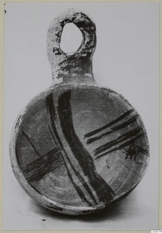 Round pottery vessel with a loop handle and broad dark painted bands, photographed against a plain background
