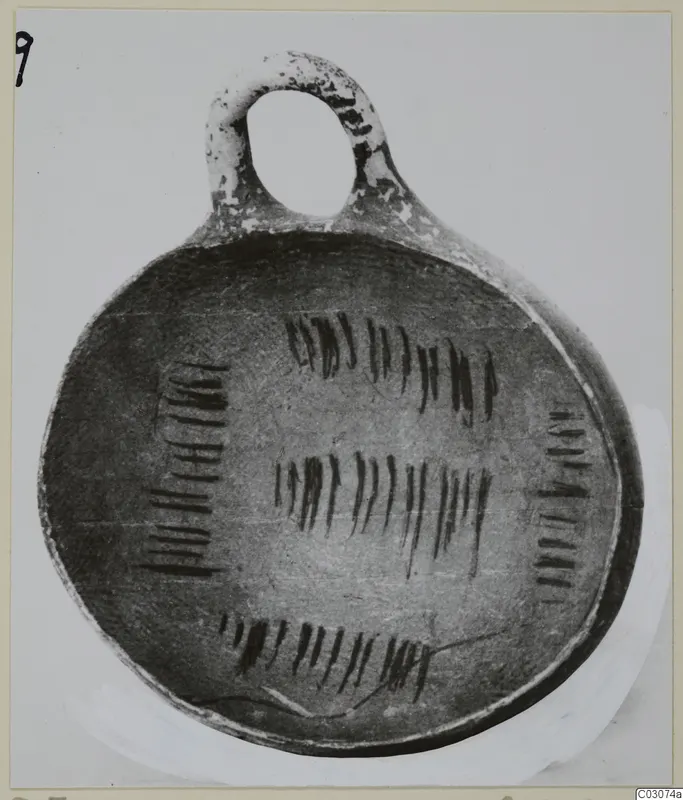 Pottery bowl with a loop handle, its interior decorated with dark vertical strokes in bands