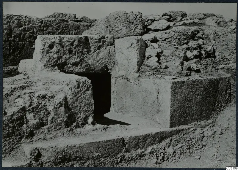 Large cut stone blocks and walls at the Vouni palace, with a dark doorway opening between them