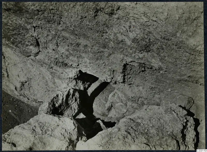 Excavated stones and a rough rock face at the palace at Vouni, seen close up.