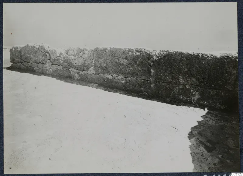 Long stone wall with a bright, bare ground surface in front, at the palace at Vouni.
