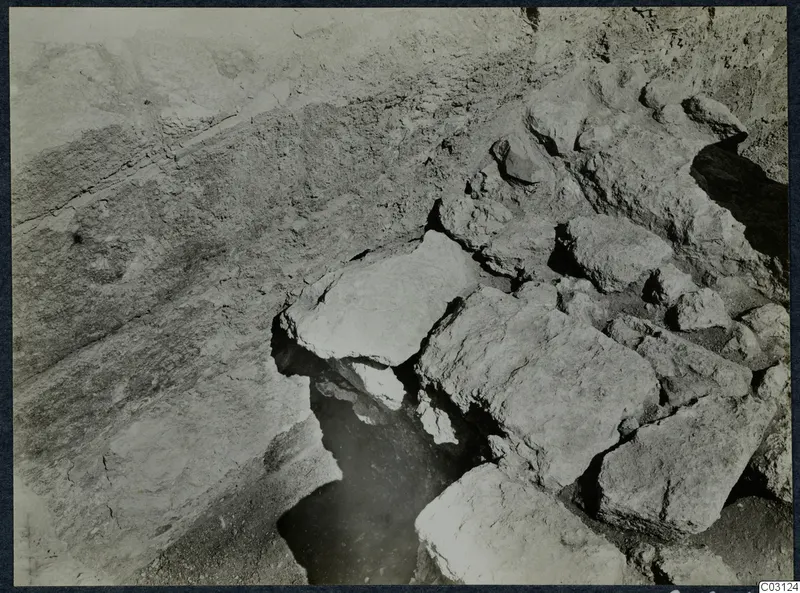 Large cut stone blocks and a dark pit during excavation at the palace at Vouni.