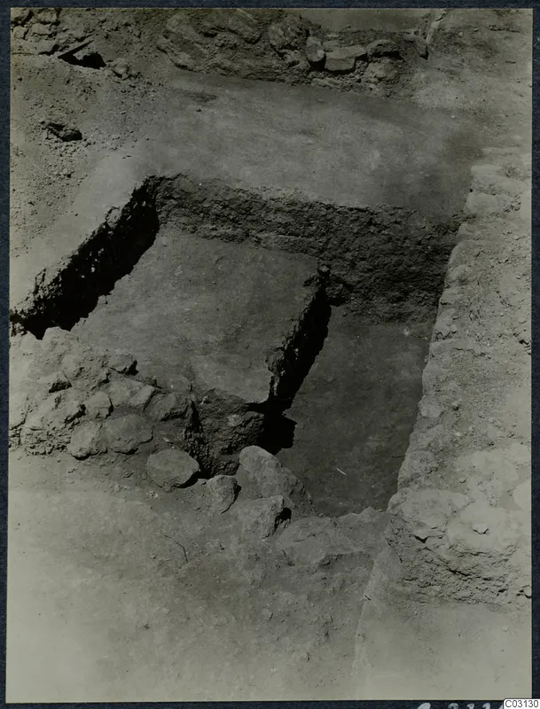 Excavation at the Vouni palace showing a square cut in the soil, with rough stone walls and loose rubble around it