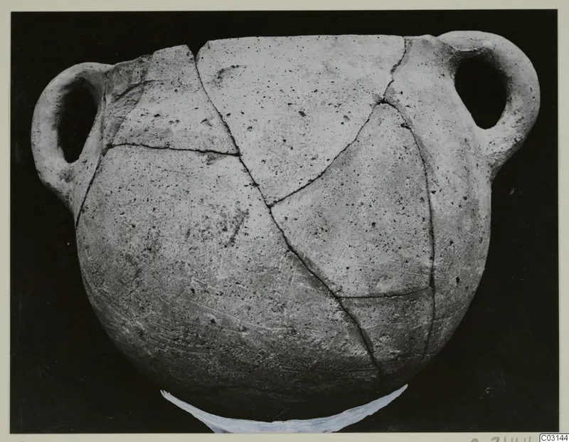 Plain White Hand-made Ware vessel with two loop handles, its broken pieces rejoined with visible cracks