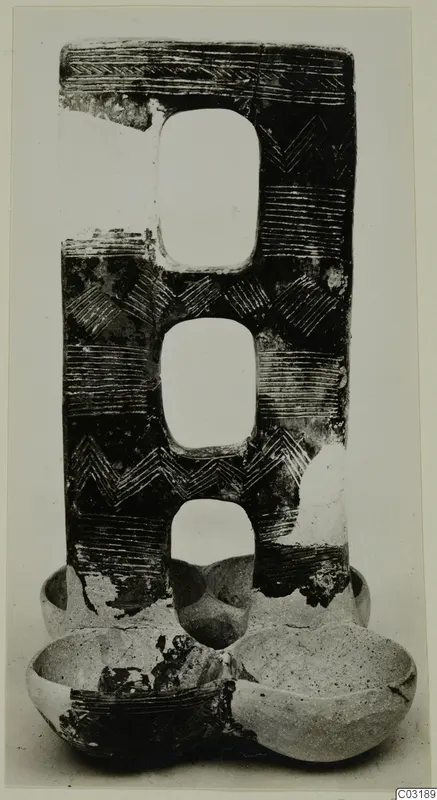 Incised pottery object with three rounded openings stacked vertically and two bowl-shaped sections at its base
