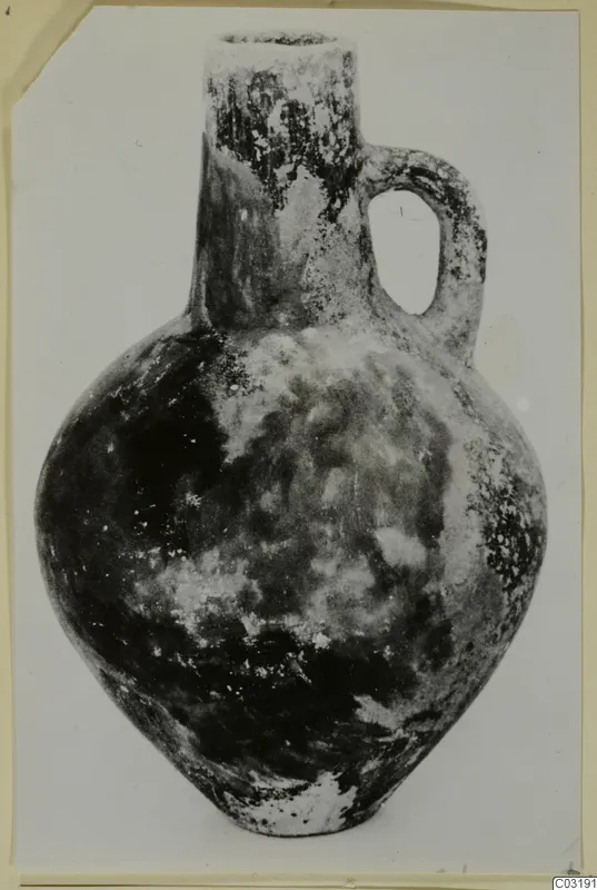 Red Polished III jug from Vomerus 81A, with a long neck, single loop handle and rounded body.