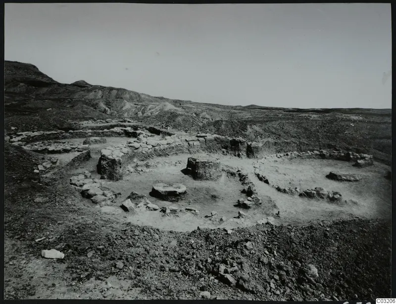 Excavated stone house foundations at Kythrea, with low walls and round stone bases on a stony hillside.