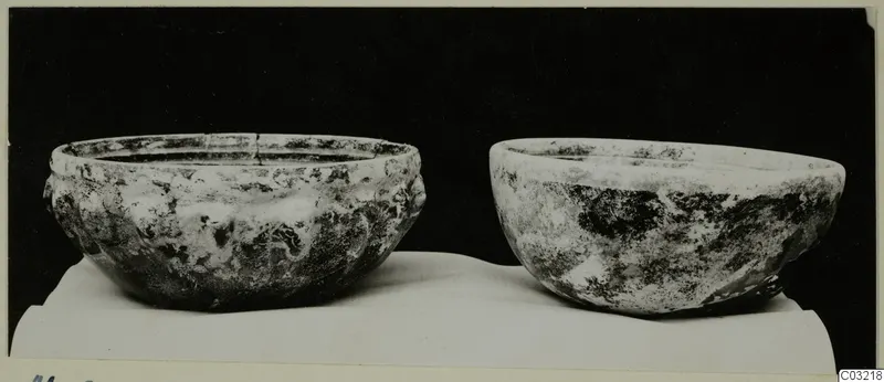 Two cast glass bowls on a white cloth against a black background, one with a ribbed outer wall and a cracked rim