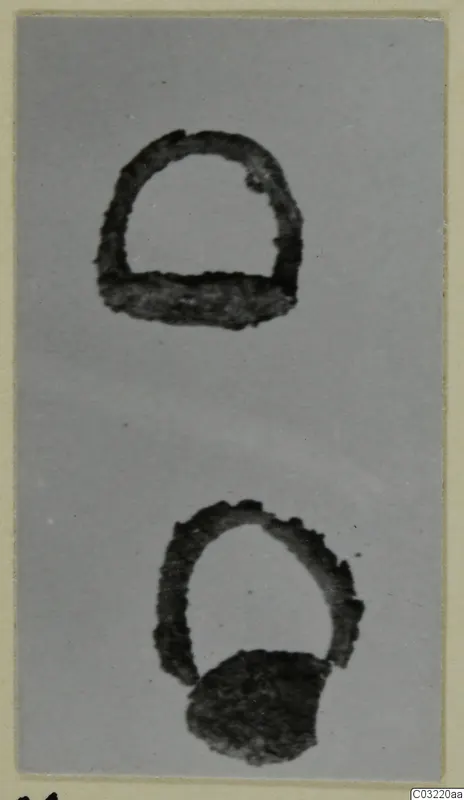 Two corroded iron objects on a plain grey background, one a semicircular loop with a flat base bar