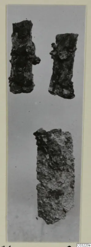 Three corroded iron objects, elongated and encrusted, shown on a grey background