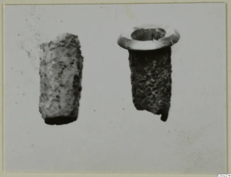 Two small corroded cylindrical objects side by side, one with a flared rim.