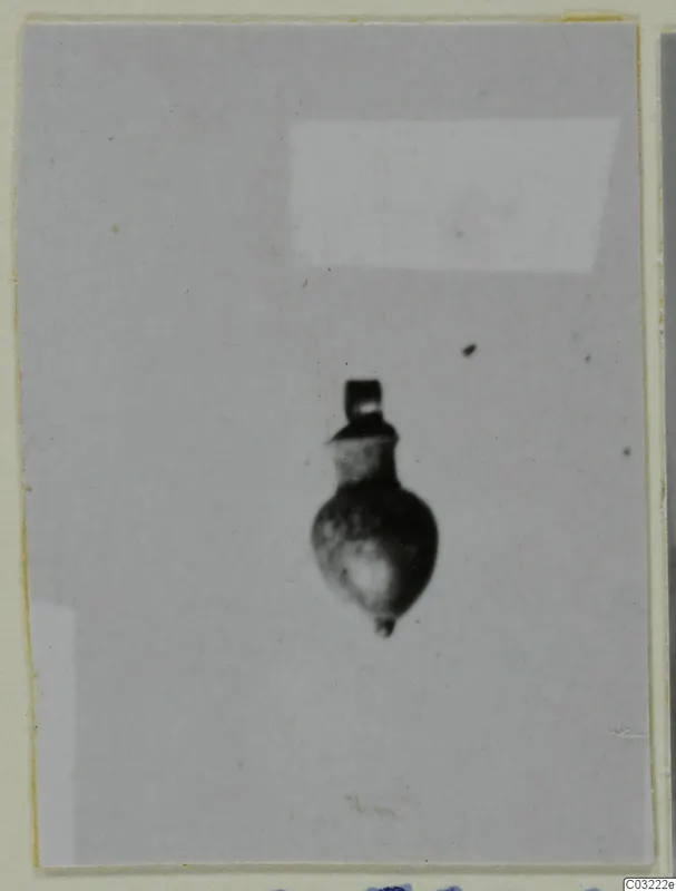 Small pendant with a loop at the top and a rounded, bulbous body, photographed on a grey ground.