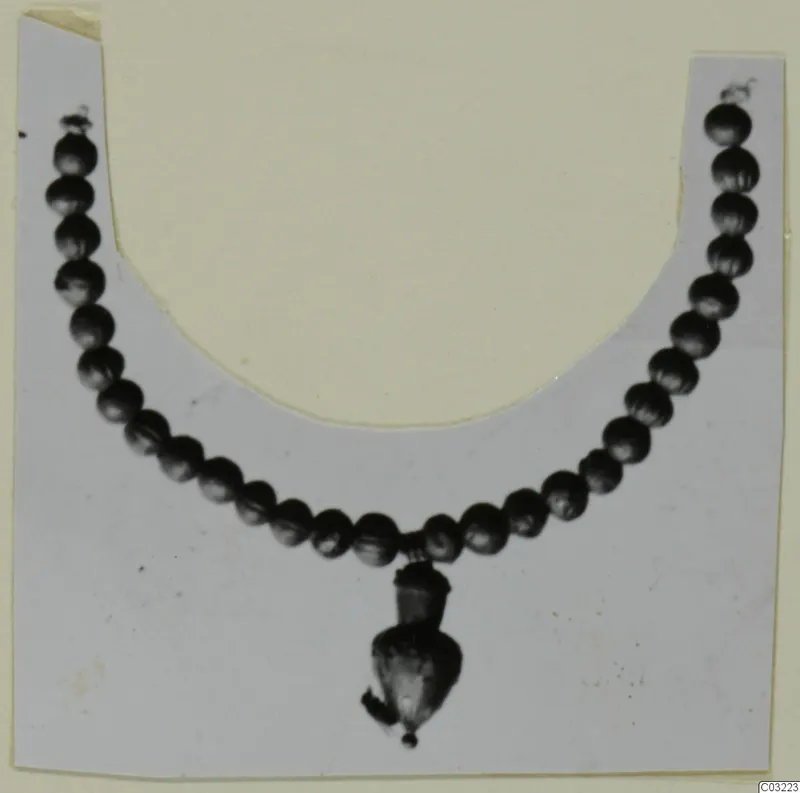 Necklace of small round dark beads with a pendant hanging from the centre