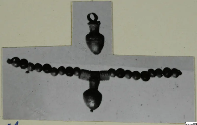 Two pendants on a strand of dark beads with a coiled-wire section at the centre, photographed on a mounted card
