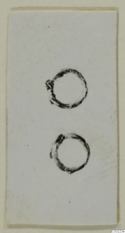 Two ring-shaped objects shown on a white card, from the Marion finds of tombs 31–45