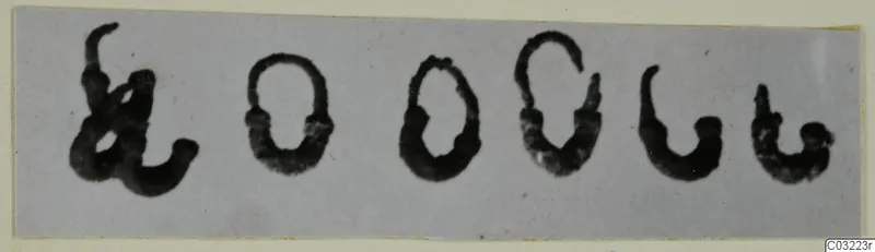 Row of six dark signs on a pale strip, shown as a find from Marion tomb 59; the signs do not look like jewellery.