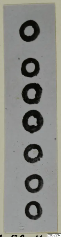 Seven dark ring-shaped objects in a vertical row on a pale background, recorded as silver
