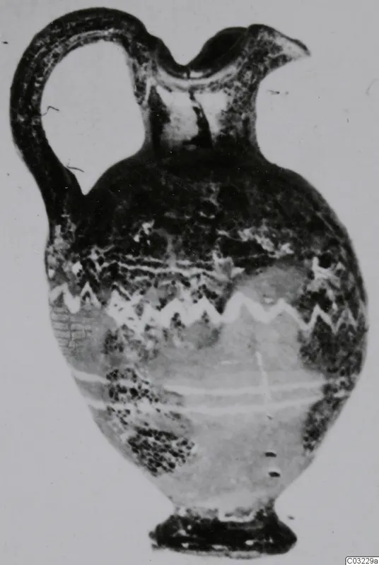 Sand-core glass jug with a loop handle and light zigzag trails