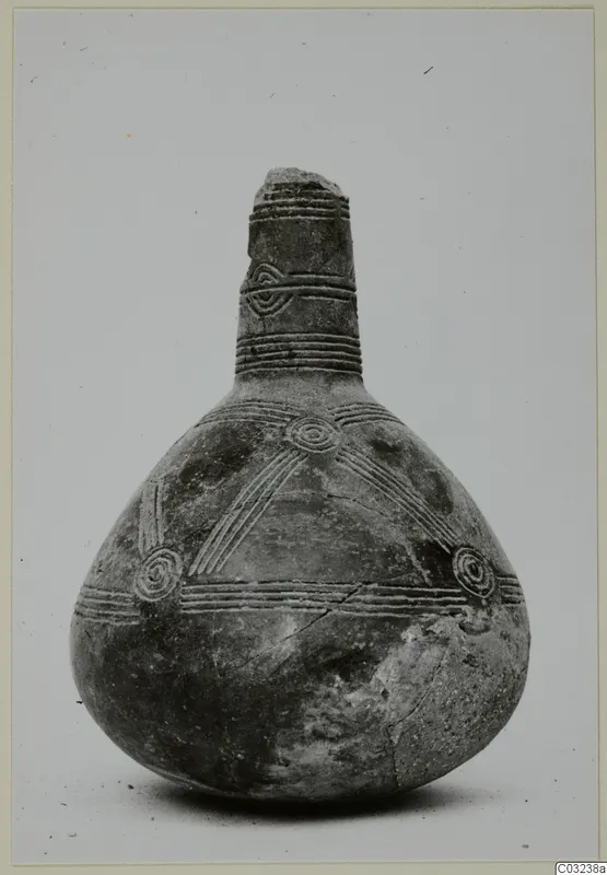 Black polished pottery vessel with a tall narrow neck, incised bands and concentric circles on the body