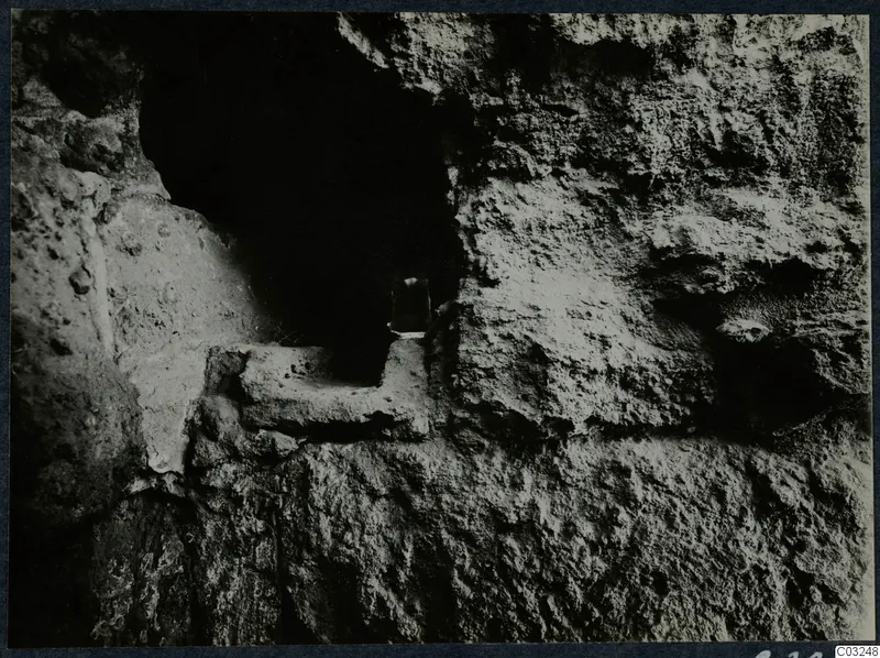 Rough stone face at Vouni palace with a dark recess and a stone ledge, seen during excavation