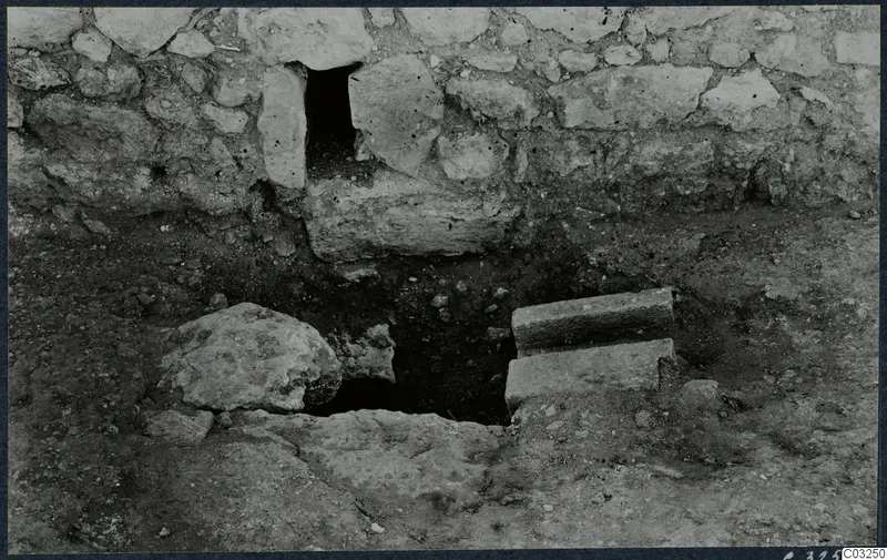 Excavated stones at Vouni palace, with a stone wall above a dug hollow in the ground