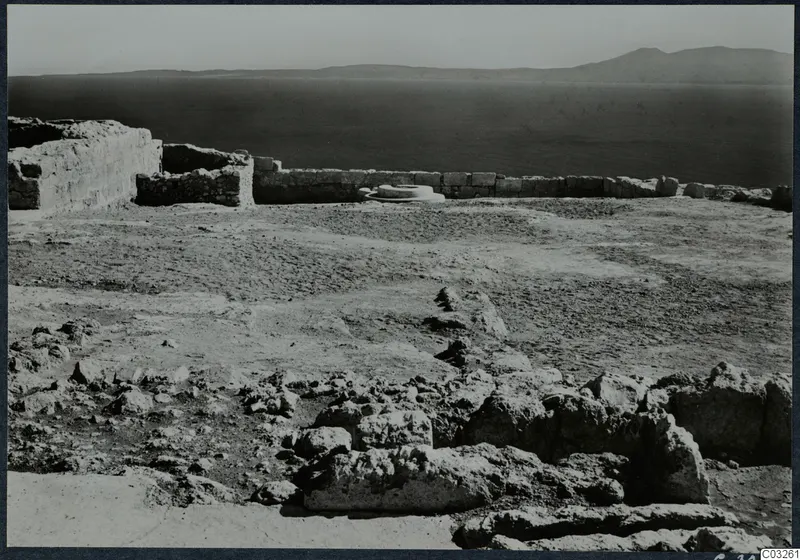 Ruined walls and scattered stones at Vouni palace, with the sea and a distant mountain range behind