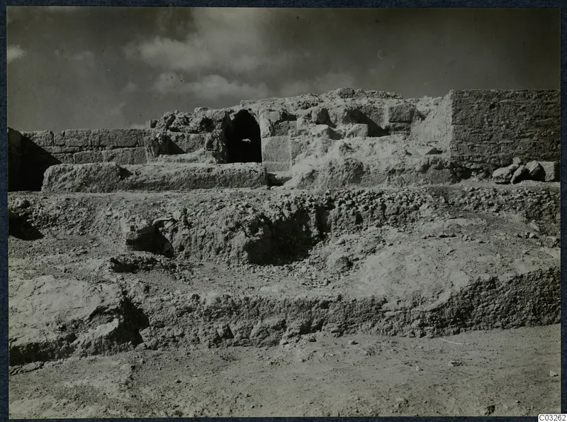 Excavated stone walls at Vouni palace, with a dark arched opening in the central wall