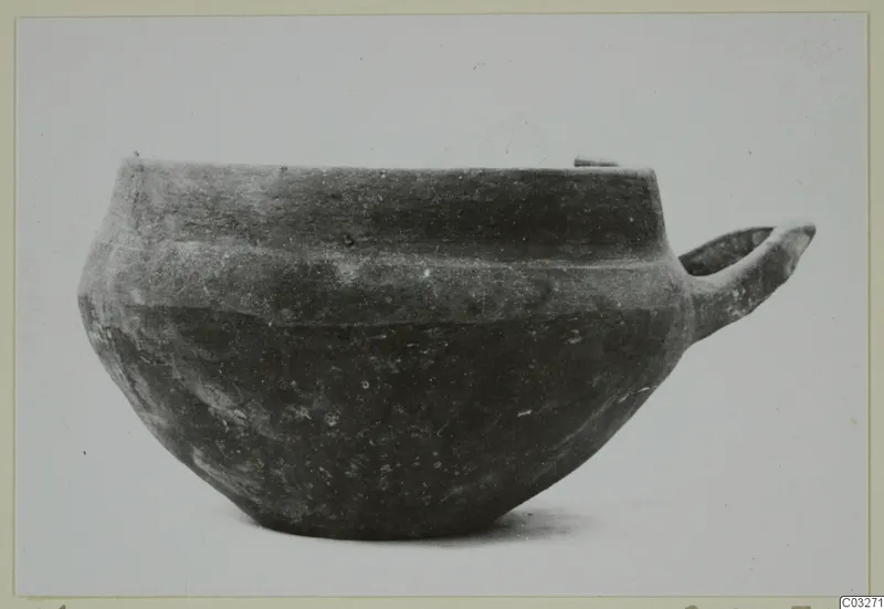 Pottery bowl with a single loop handle from Milia, shown in side view.