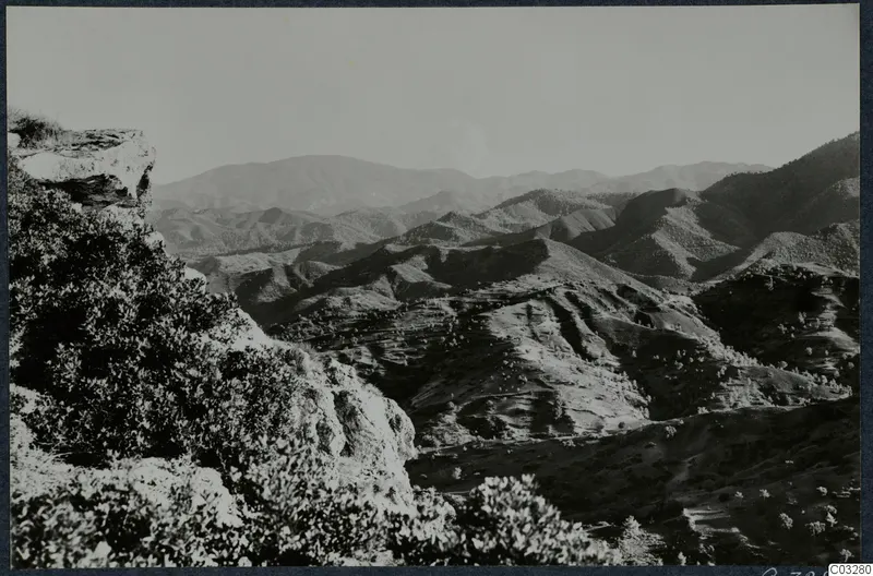 Landscape at Vouni with rolling hills, a rocky outcrop and shrubs in the foreground.