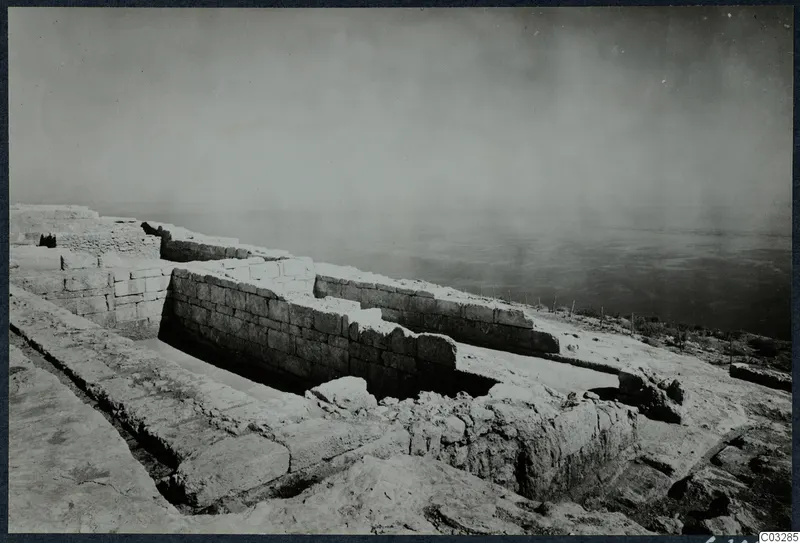 Ancient stone walls and a paved area on a height at Vouni, with hazy sea beyond.