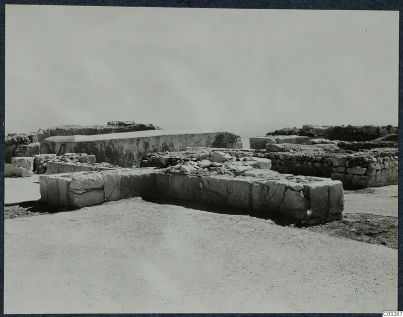 Excavated stone walls and blocks at the Vouni palace, with a large block structure behind them.
