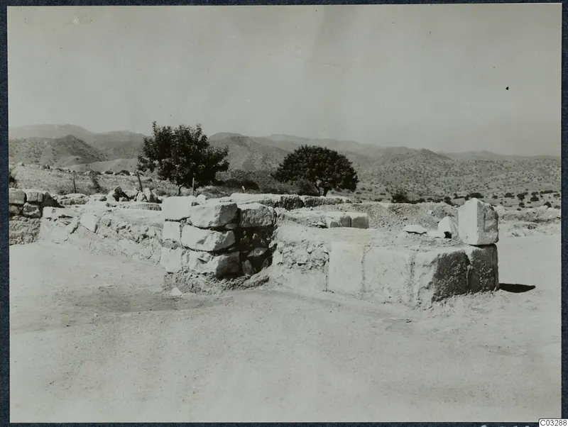 Ruined stone wall of large squared blocks at Vouni palace, with trees and hills behind