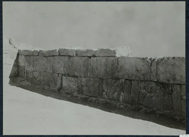 Long wall of large squared stone blocks running diagonally across a pale ground at Vouni palace.