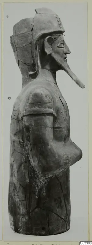 Terracotta figure in side profile with a helmet-like headdress and a long projecting face, from Ayia Irini