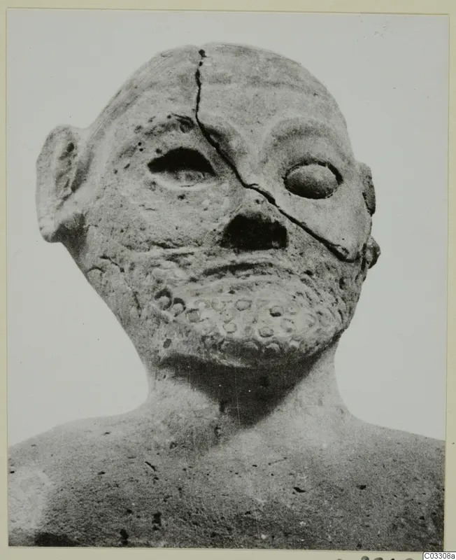 Terracotta head and upper body with a cracked face, a narrow slit eye, and a band of small round impressions on the chin