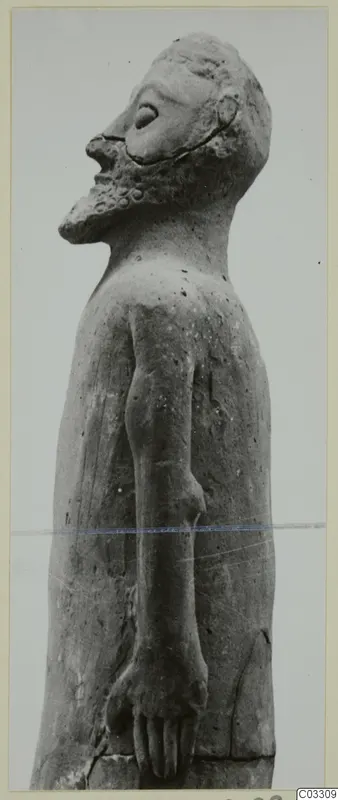 Terracotta statue of a standing bearded man with head tilted up, photographed from the side.