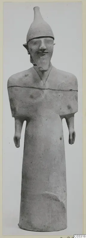 Terracotta statue of a standing figure with a tall conical headdress and short stub arms, shown against a plain grey background