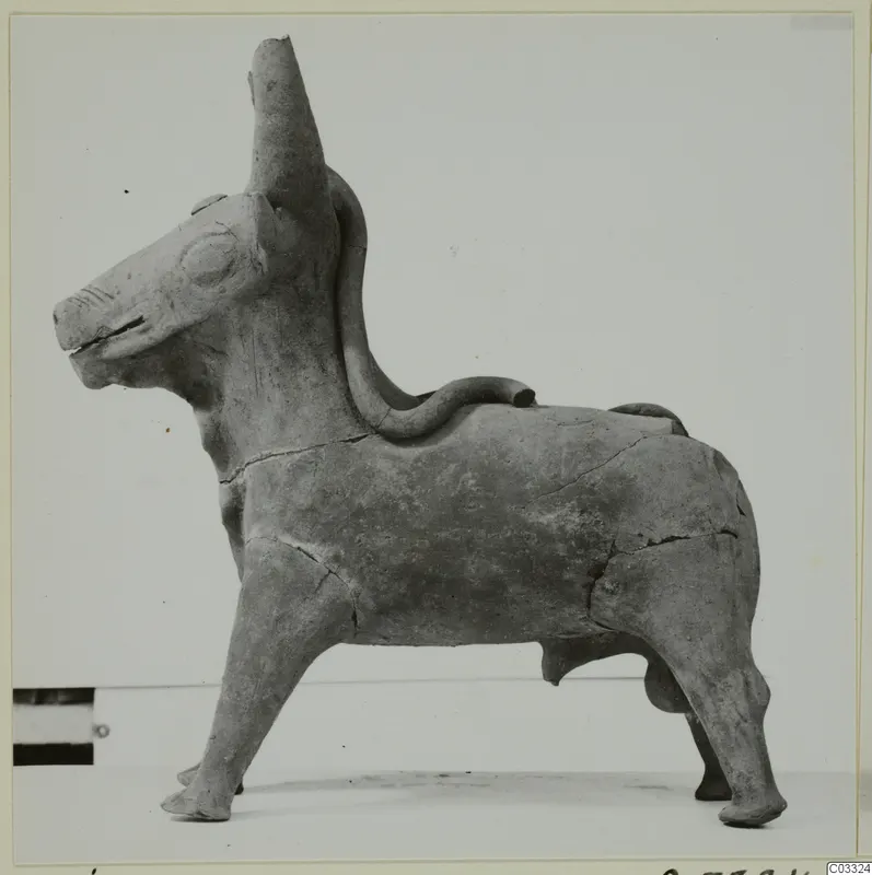Terracotta figurine of a standing bull with a tall tubular spout on its head and a looped handle on its back